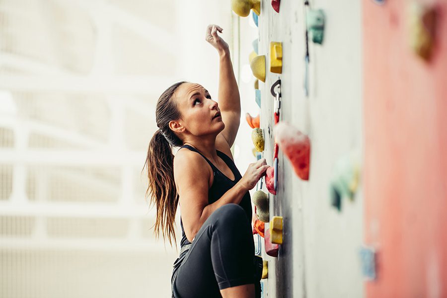 Climbing Gym Insurance - Side View of Professional ClimberFemale at a Rock Climbing Wall in the Gym