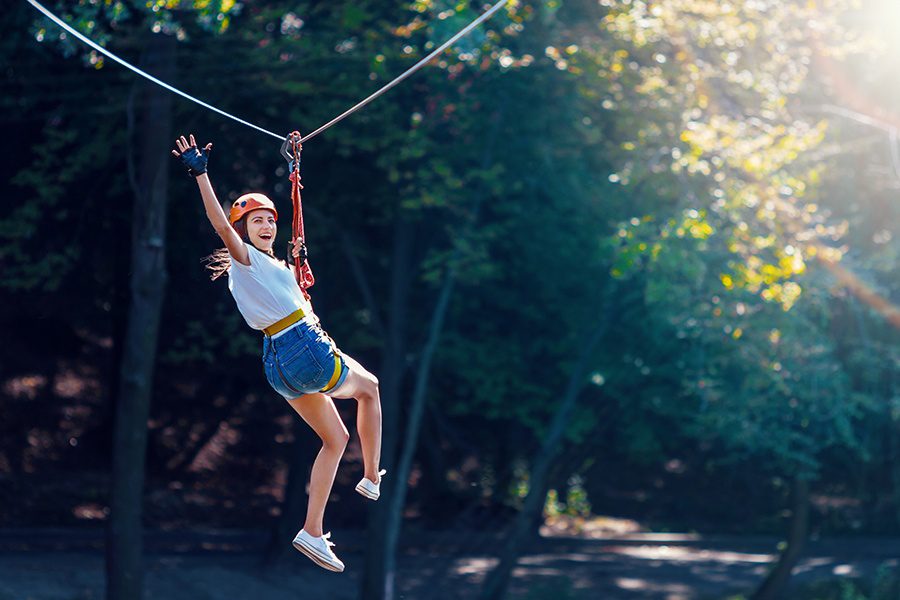 Zipline and Aerial Park Insurance - Happy Women Gliding on a Zipline in Adventure Park