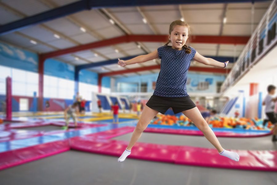 Trampoline Park Insurance - Cheerful Young Girl With Pigtails and Smiling While Jumping on a Trampoline