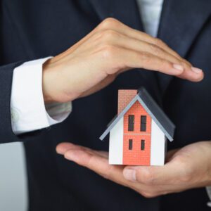 An image of a man in a suit holding a small model of a house