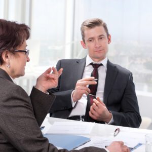 An image of two people dressed in business attire discussing a document with a mature woman
