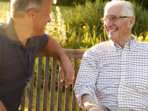 Two older men talking on a park bench outside