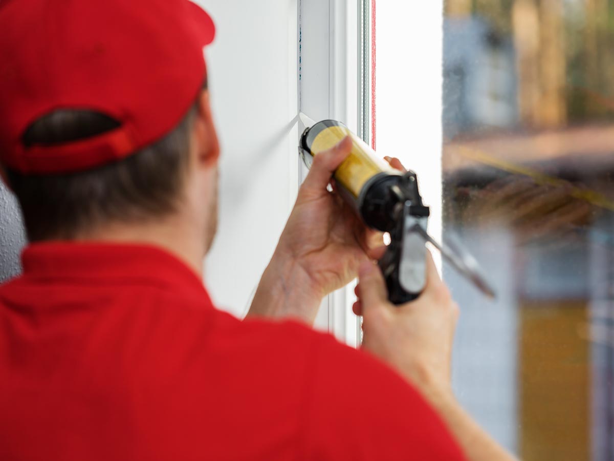 Man applying sealant to cracks around window