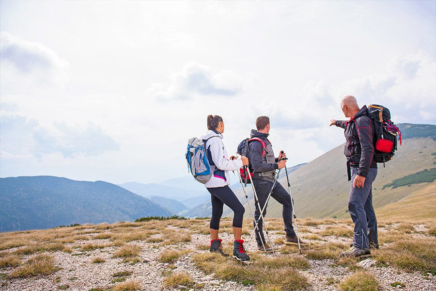 Guided Tour Operators Insurance - Couple Hiking Over Moutains Asking for Directions from another Hiker on to of a Mountain on a Beautiful Day with a Beautiful View