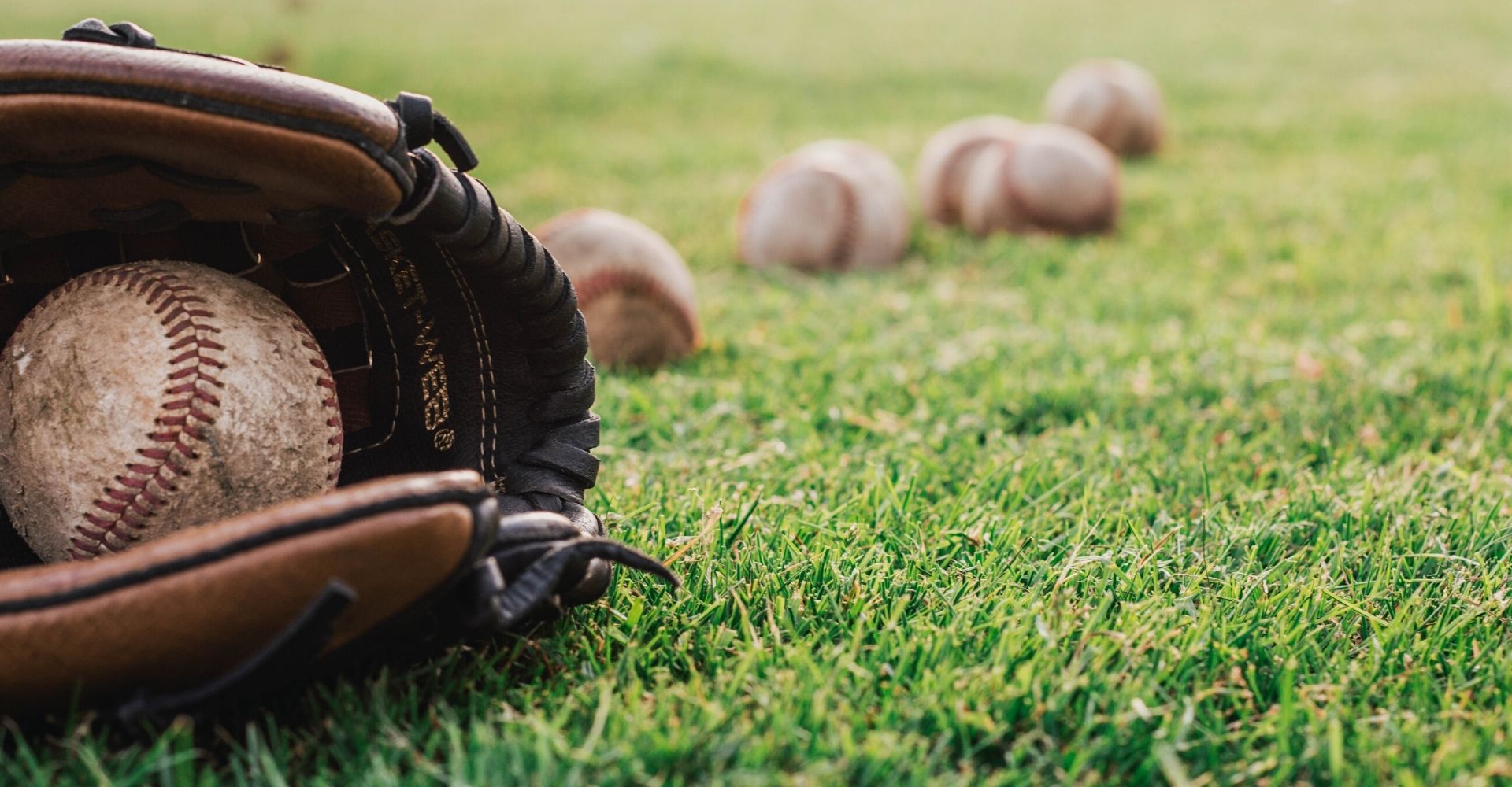 baseball glove on field with multiple baseballs