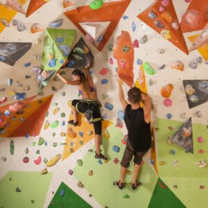 man and woman rock climbing at climbing gym
